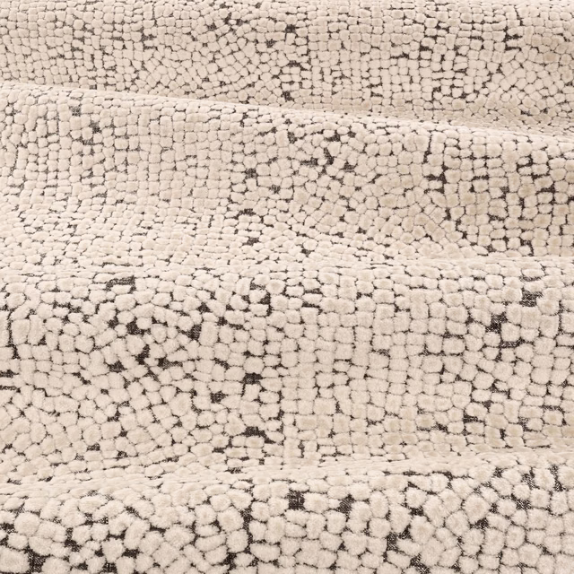 Warm ivory looped upholstery fabric with scattered charcoal flecks and nubby texture