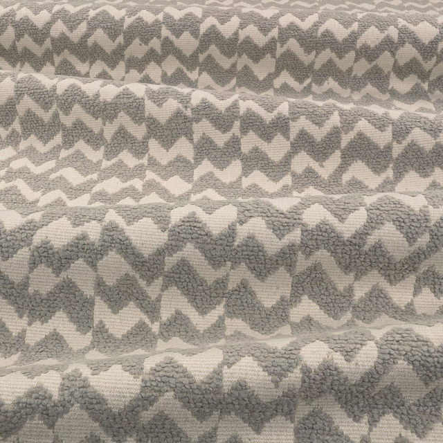 Mottled stone-grey and ivory textile with raised irregular chevron weave
