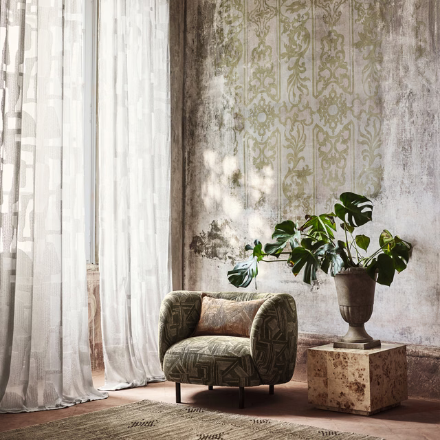 Olive-green geometric upholstery on a rounded armchair, with dark linear motifs