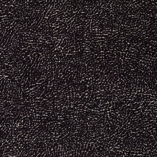 Black woven upholstery with dense ivory flecks and irregular rippled texture