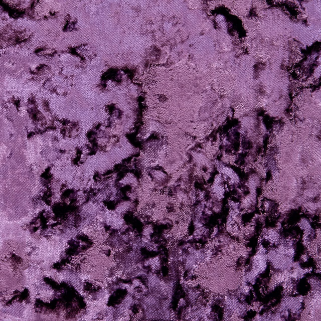 Grape-purple textured fabric with scattered black abstract markings and a softly nubby surface