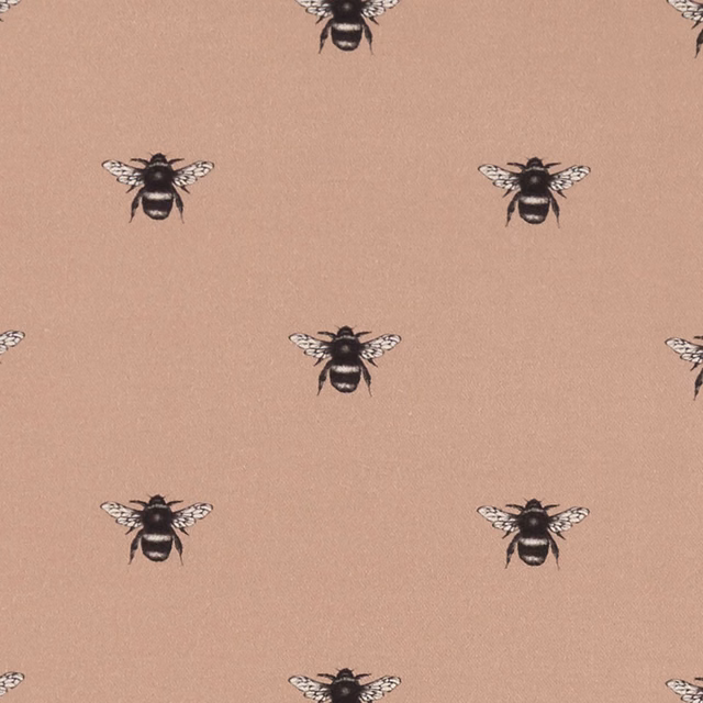 Blush pink fabric with spaced black-and-cream bee motifs and fine texture