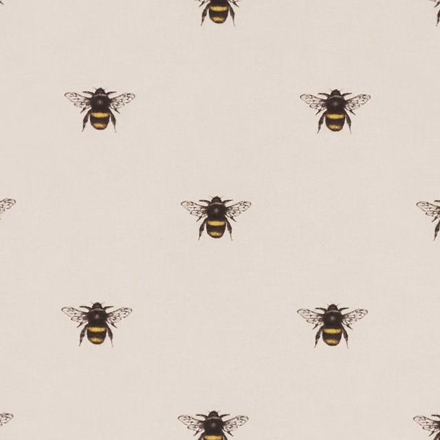 Warm ivory fabric with spaced black-and-gold bee motifs and fine woven texture