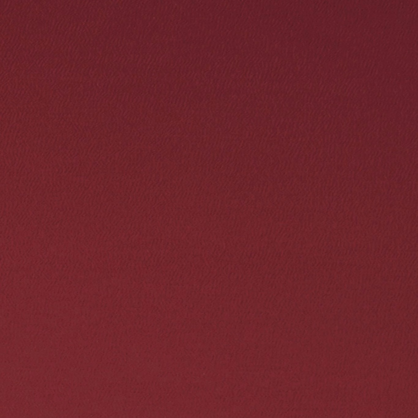 Close-up of deep crimson fabric with a fine, softly rippled woven texture