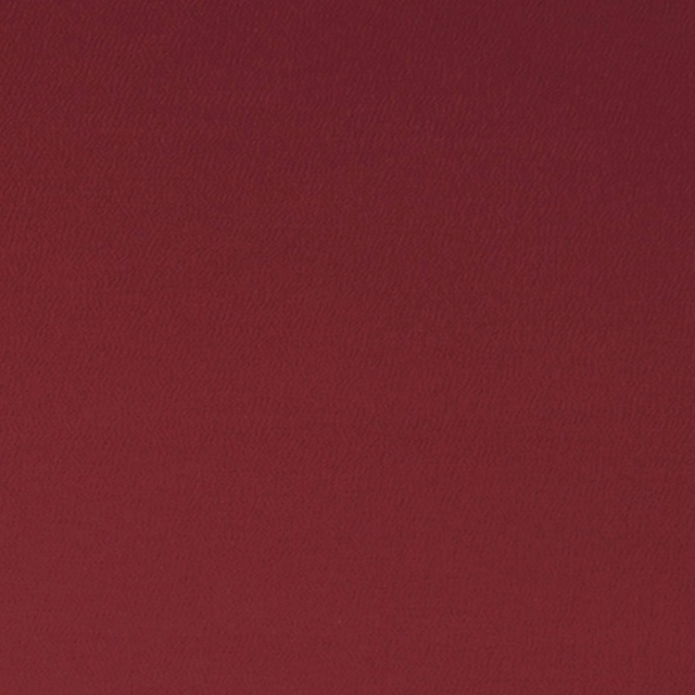 Close-up of deep crimson fabric with a fine, softly rippled woven texture