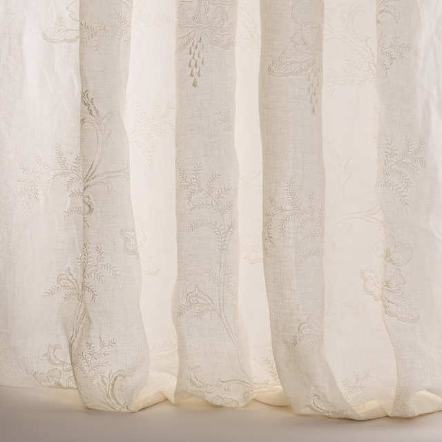 Sheer ivory voile curtains with trailing floral embroidery and soft linen texture