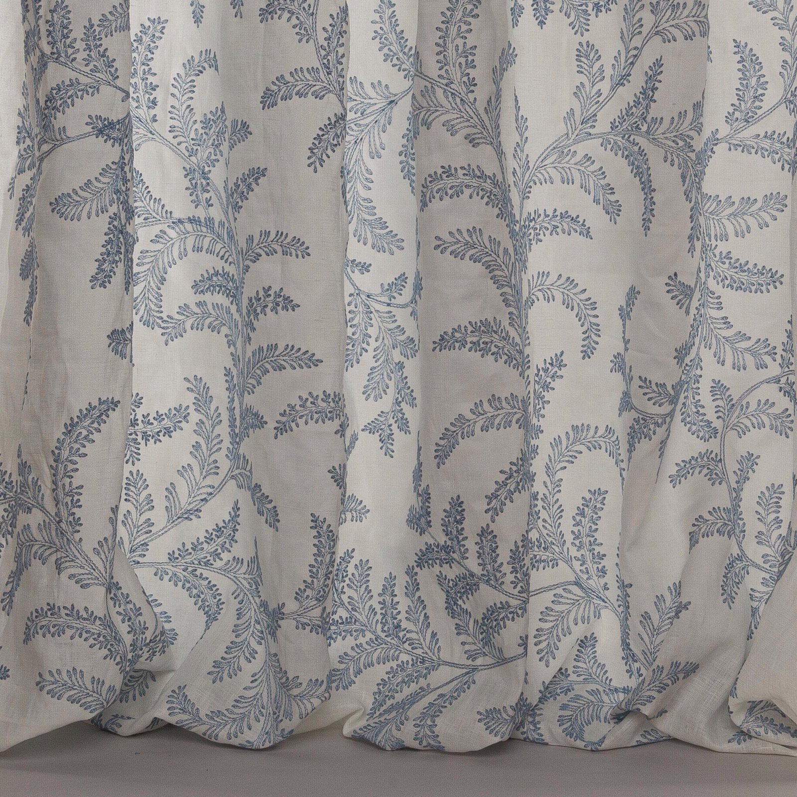 Pale linen-blend fabric with trailing blue botanical embroidery-style print