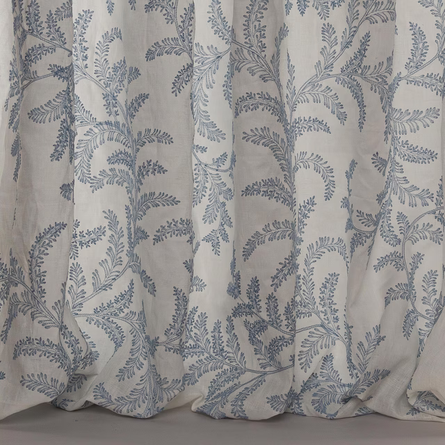Pale linen-blend fabric with trailing blue botanical embroidery-style print