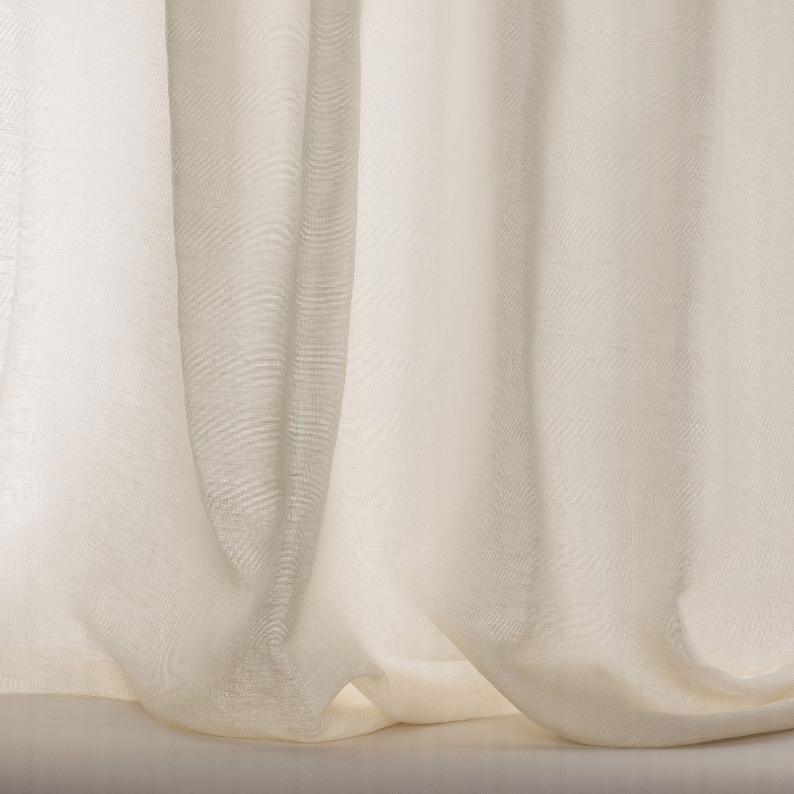 Pale cream sheer curtain fabric with a soft natural slub and fluid folds