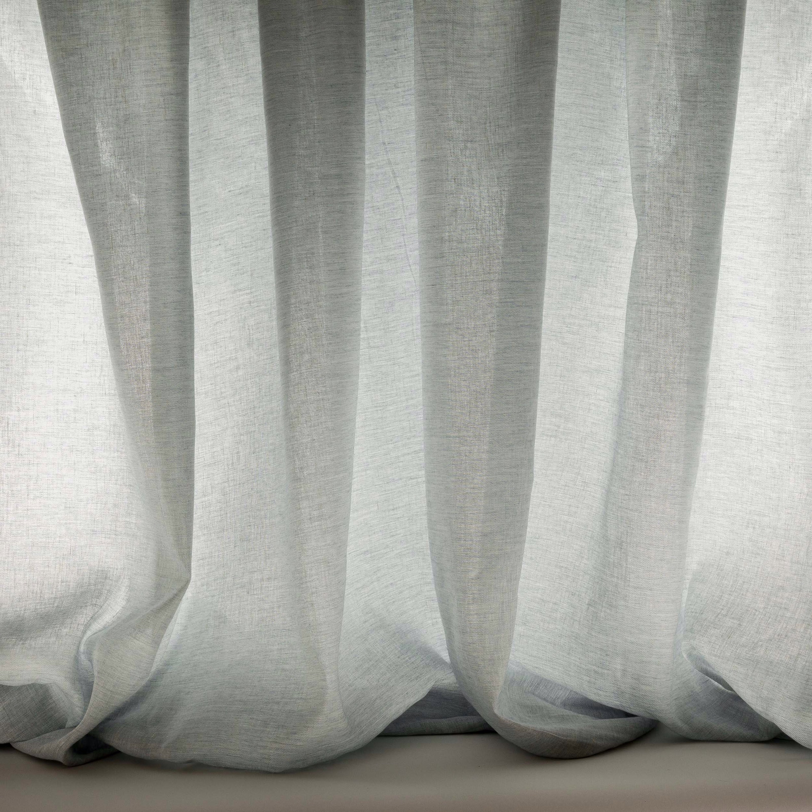 Pale misty blue sheer fabric hanging in soft vertical folds