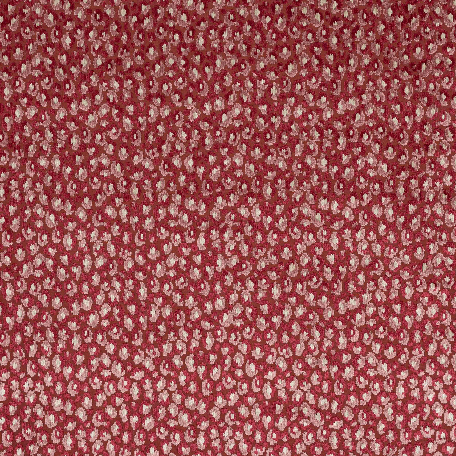 Close-up of small cream floral motifs on a warm ruby-red woven fabric