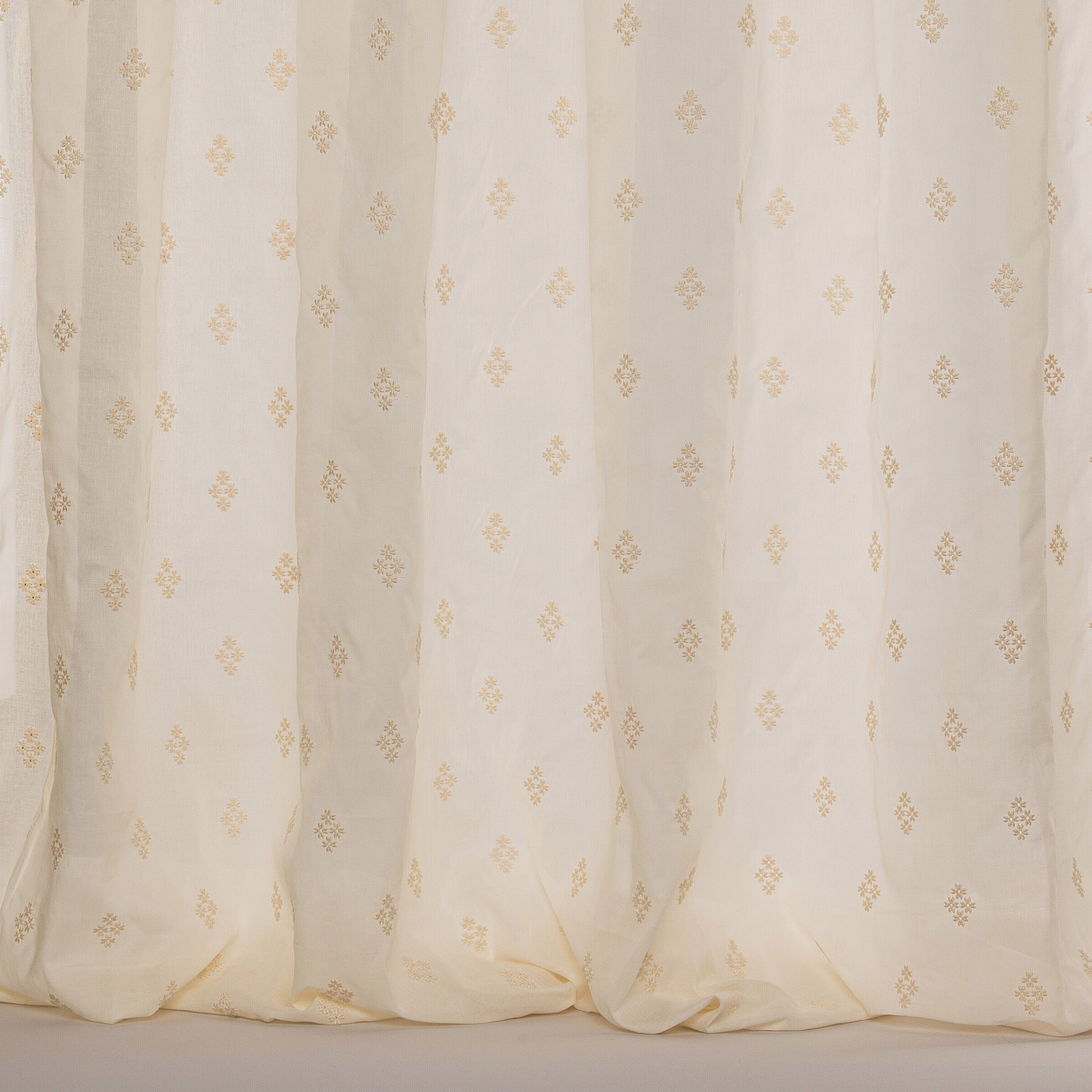 Cream sheer curtain fabric with tiny damask motifs and soft vertical folds