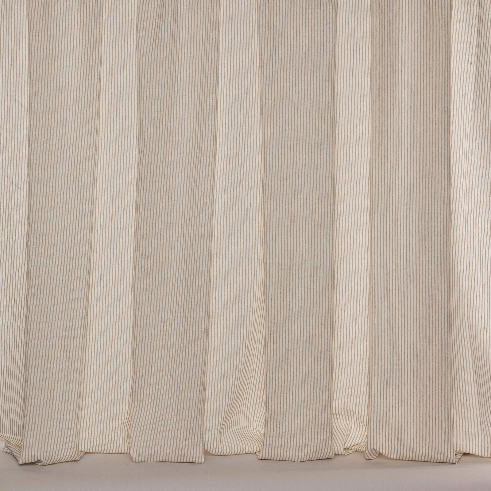 Wide cream-beige sheer fabric with fine vertical pinstripes hanging in soft folds