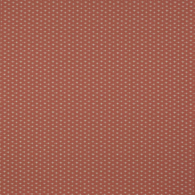 Coral terracotta woven fabric with tiny pale dot motif on a textured ground