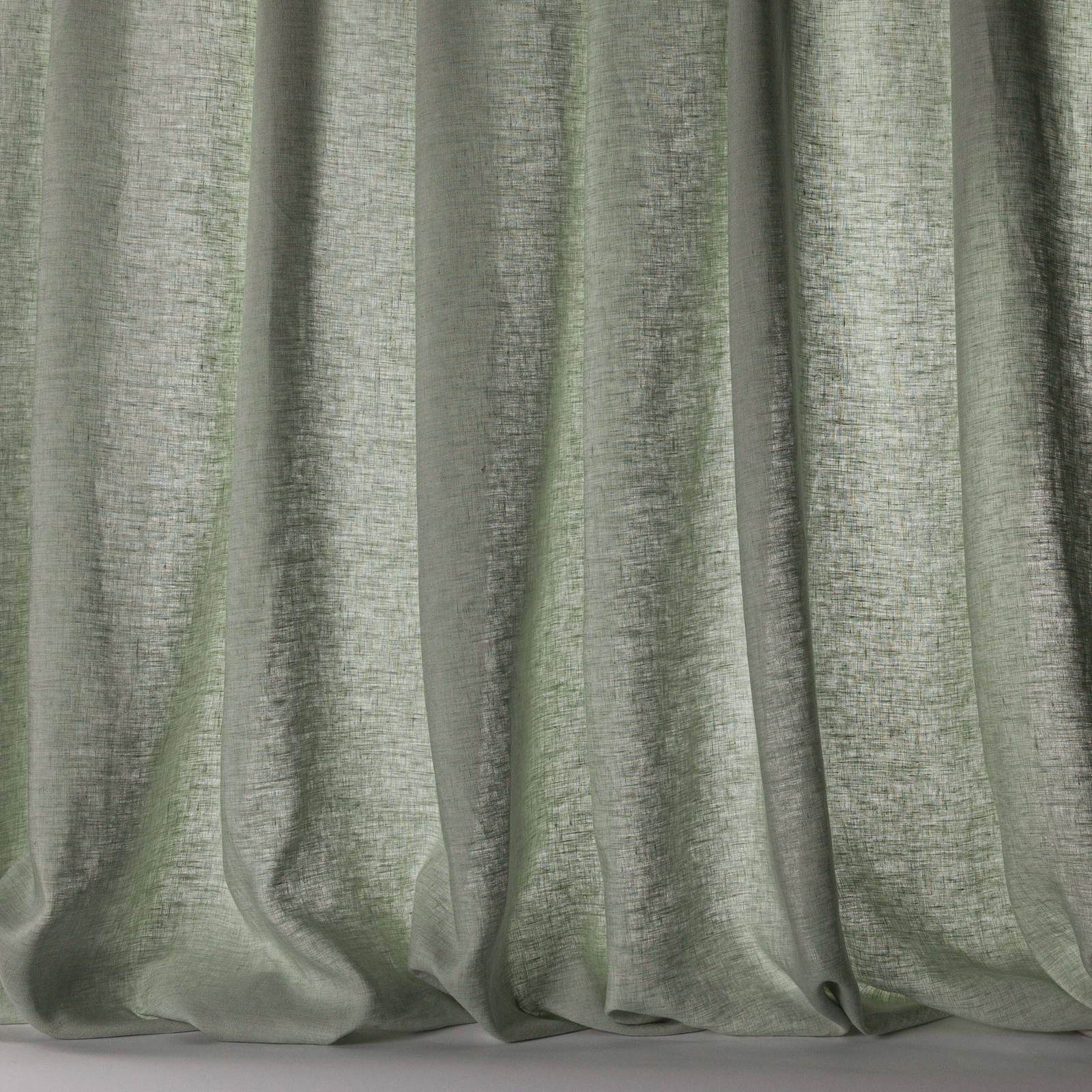 Soft celadon green linen sheer curtain with a fine slubbed weave and gentle folds