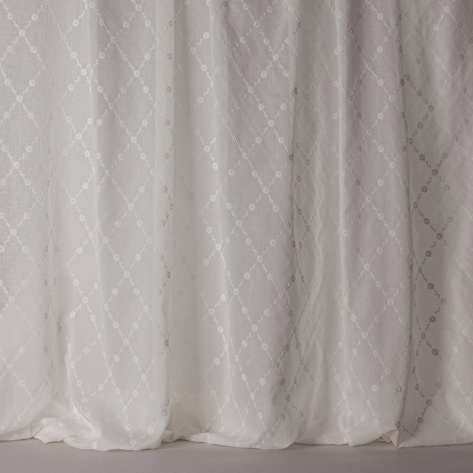 Soft white sheer curtain fabric with a subtle trellis lattice pattern