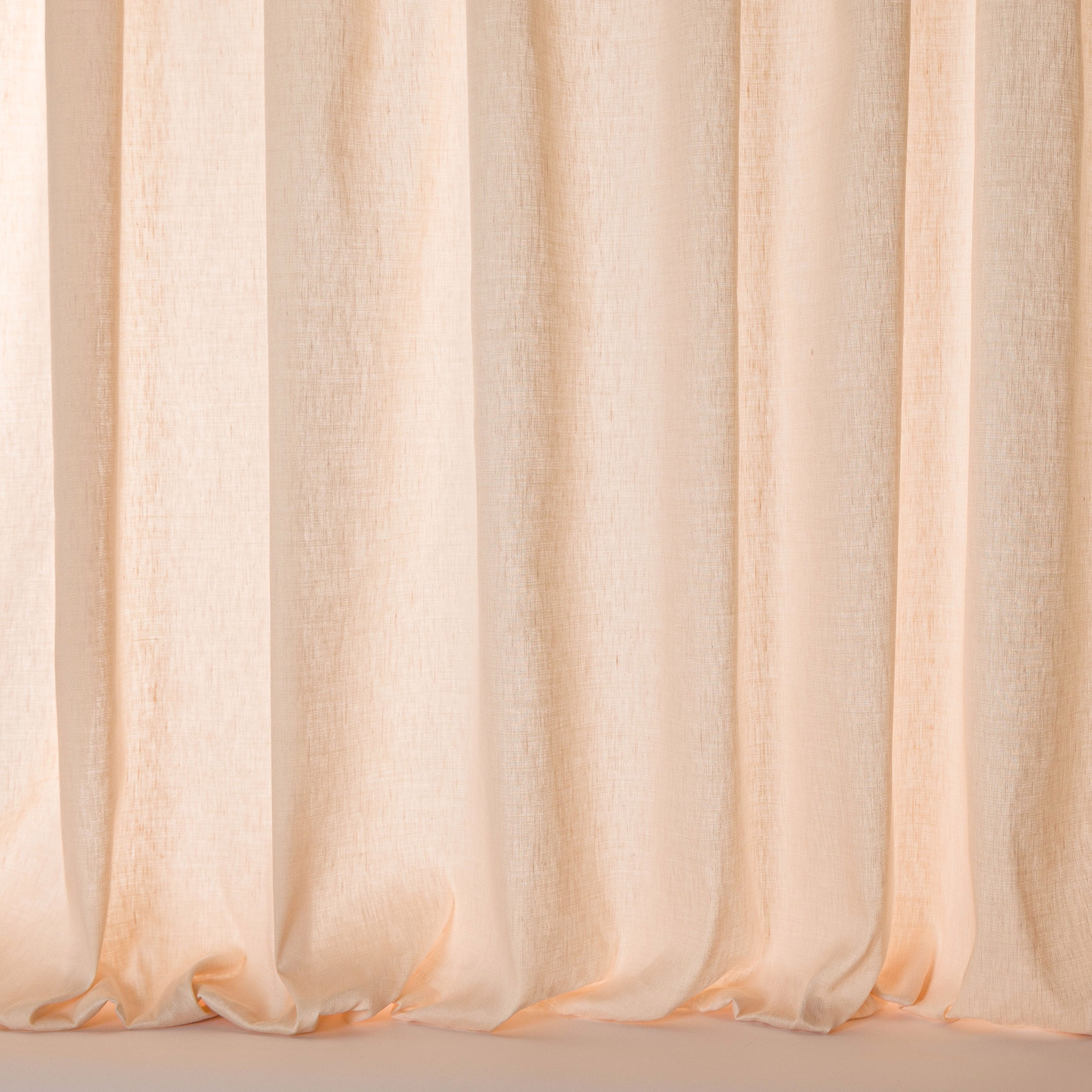 Soft blush peach sheer fabric hanging in gentle vertical folds