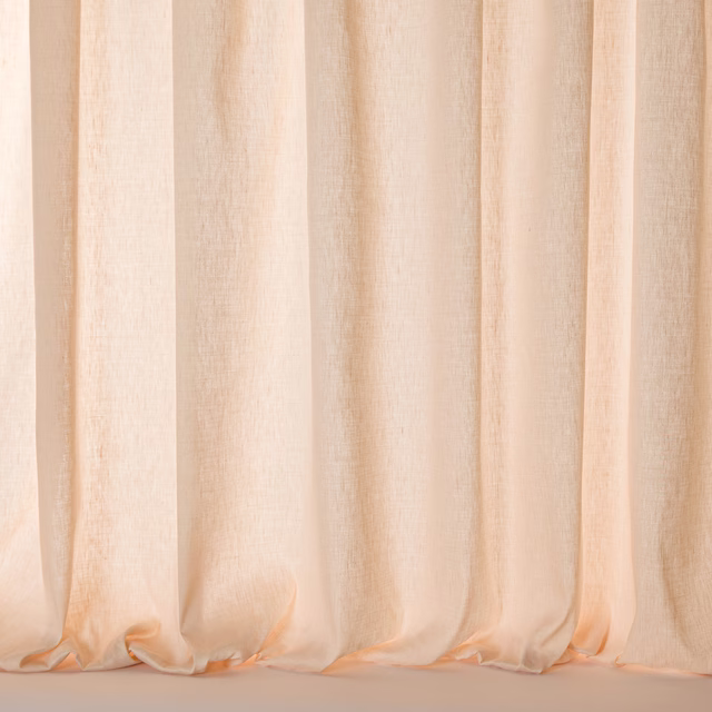 Soft blush peach sheer fabric hanging in gentle vertical folds