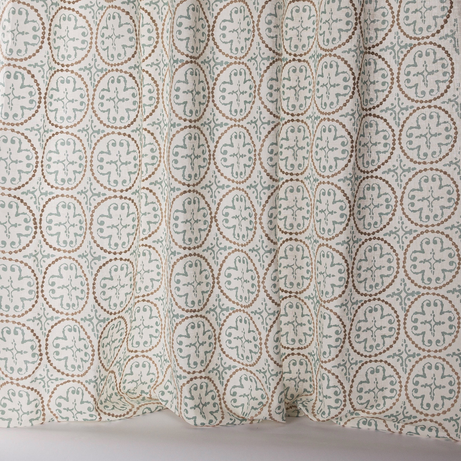 Sheer patterned fabric with soft old blue medallions on a pale ground