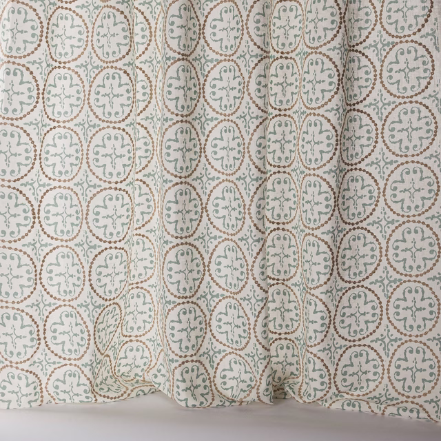 Sheer patterned fabric with soft old blue medallions on a pale ground