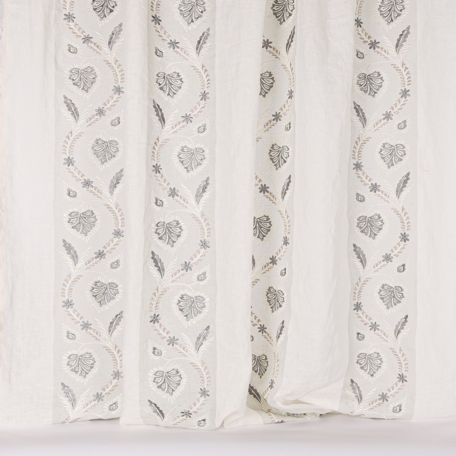 Pale sheer fabric with trailing old-blue botanical embroidery and leaf motifs