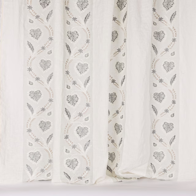 Pale sheer fabric with trailing old-blue botanical embroidery and leaf motifs