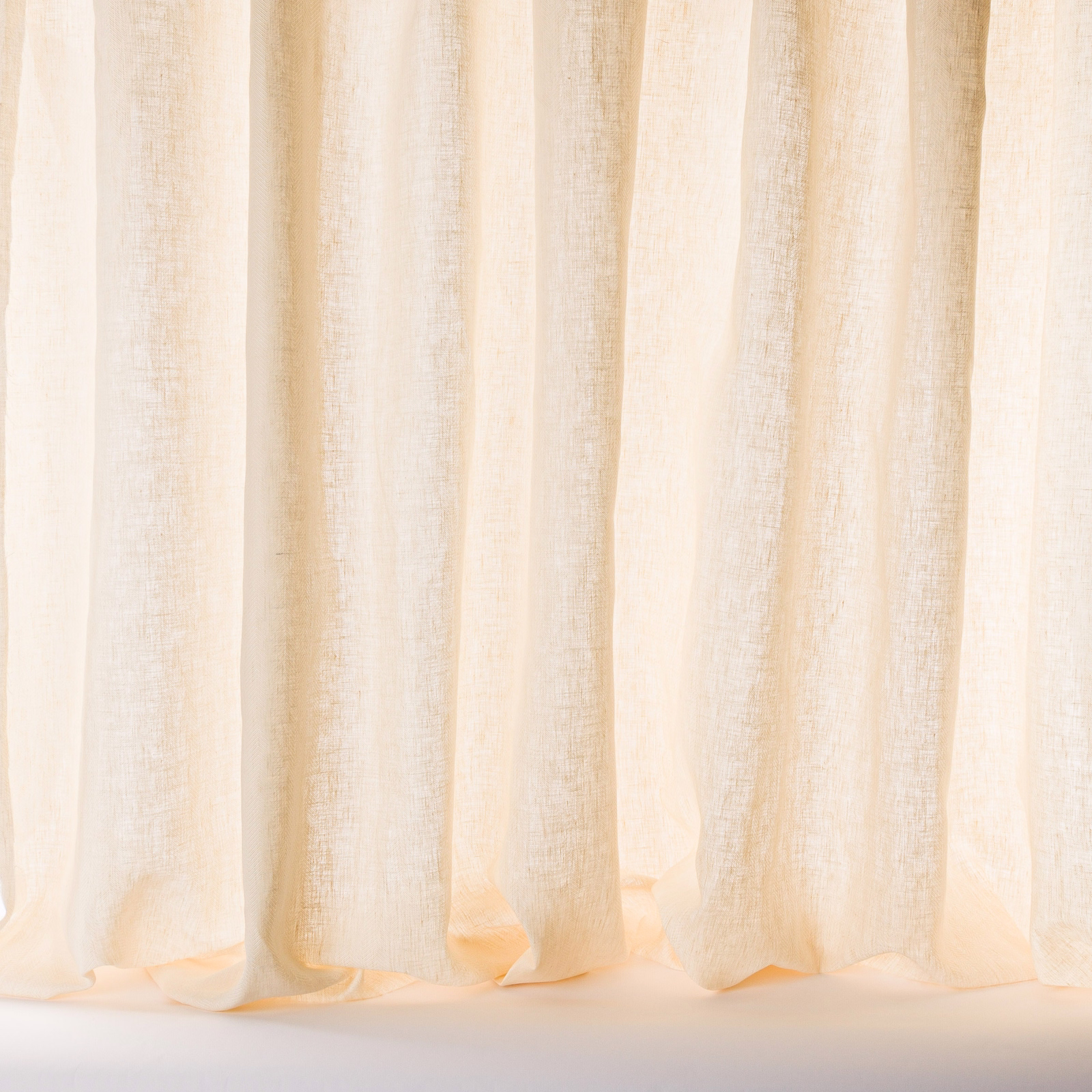 Sheer warm cream linen curtain fabric with a visible natural weave and soft folds