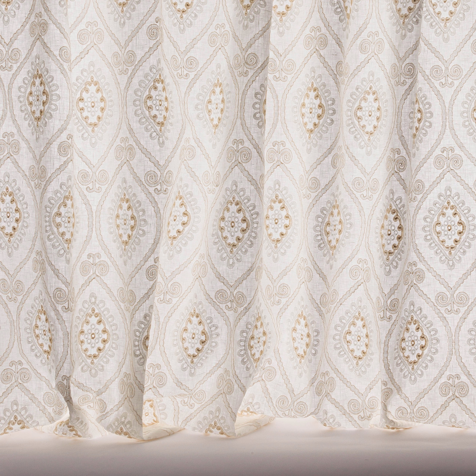 Pale beige sheer curtain fabric with repeating diamond damask motif and subtle gold accents