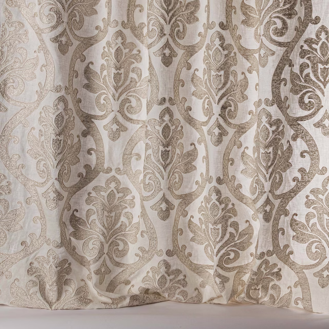 Sheer beige damask fabric with large scrolling motifs and soft woven texture
