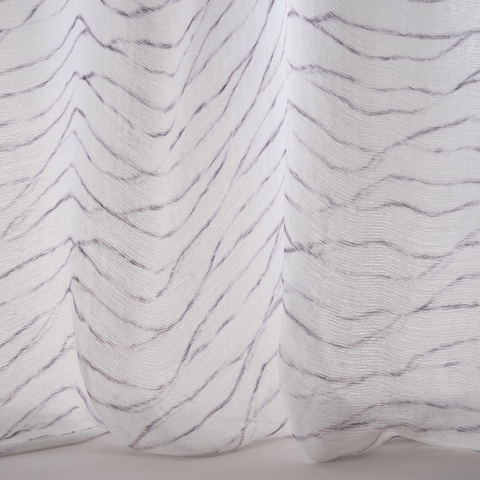 Soft white fabric with charcoal wavy chevron tracery and fluid drape