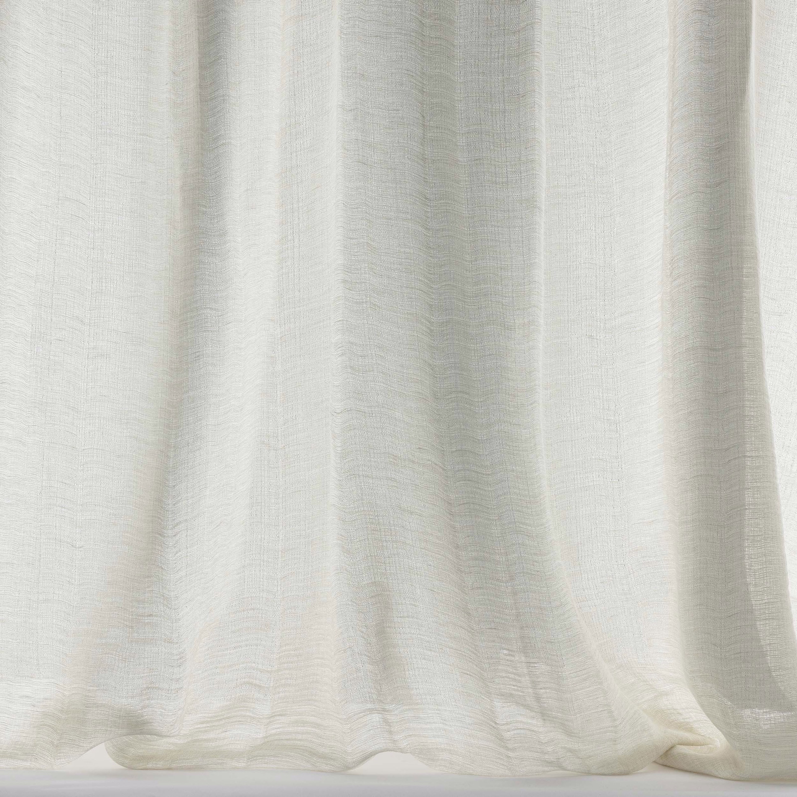 Soft cream linen-wool fabric draped in gentle folds with a matte texture