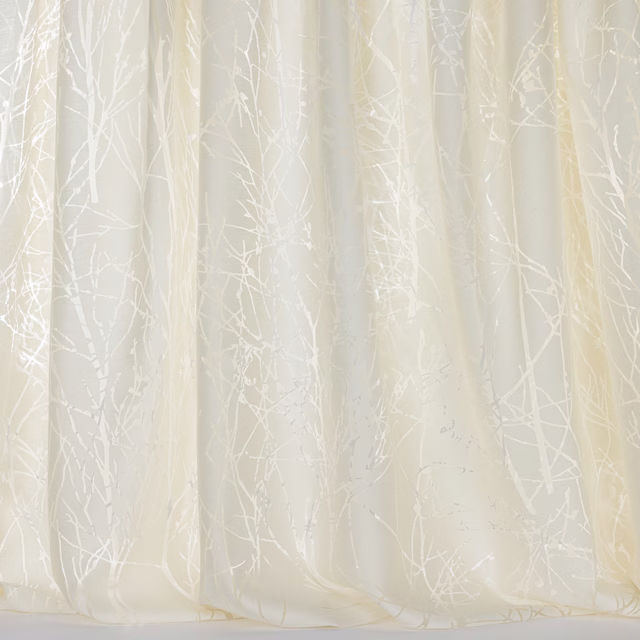 Cream sheer curtain fabric with pale tree-branch pattern and soft vertical folds