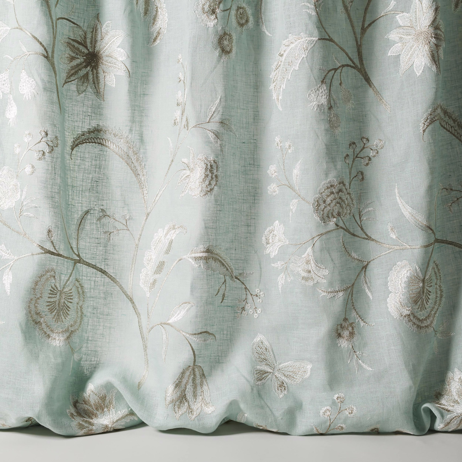 Pale old blue sheer fabric with large embroidered floral stems and blossoms