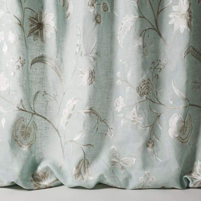 Pale old blue sheer fabric with large embroidered floral stems and blossoms
