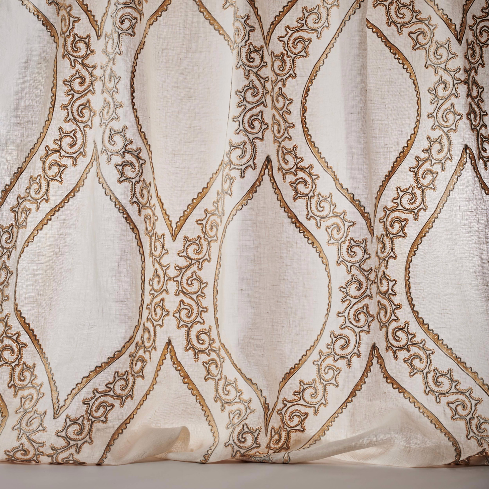 Sheer ivory fabric with pale gold scrolling lattice embroidery
