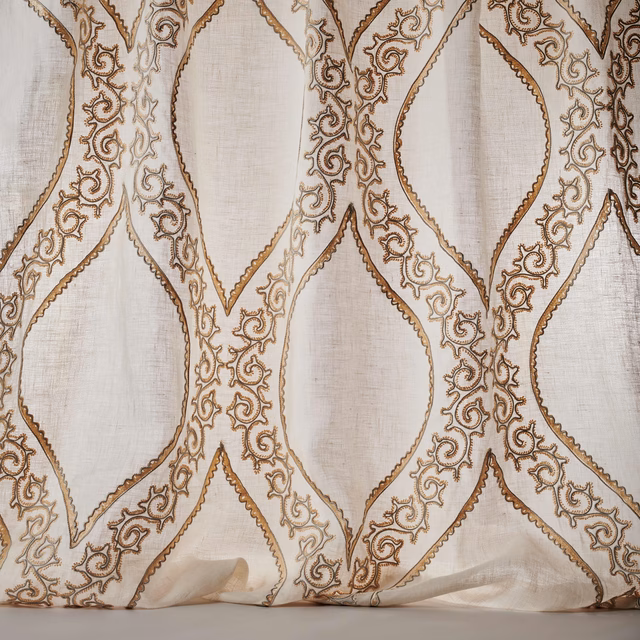 Sheer ivory fabric with pale gold scrolling lattice embroidery