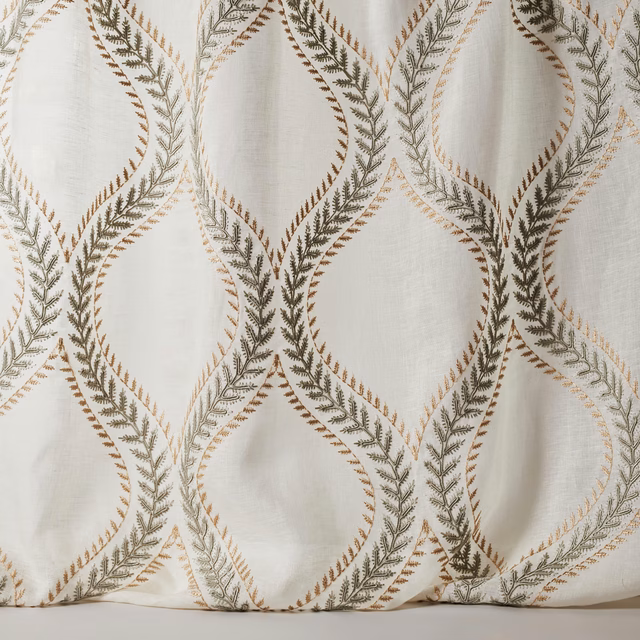 Cream-beige sheer fabric with large looping embroidered leaf pattern in olive and tan