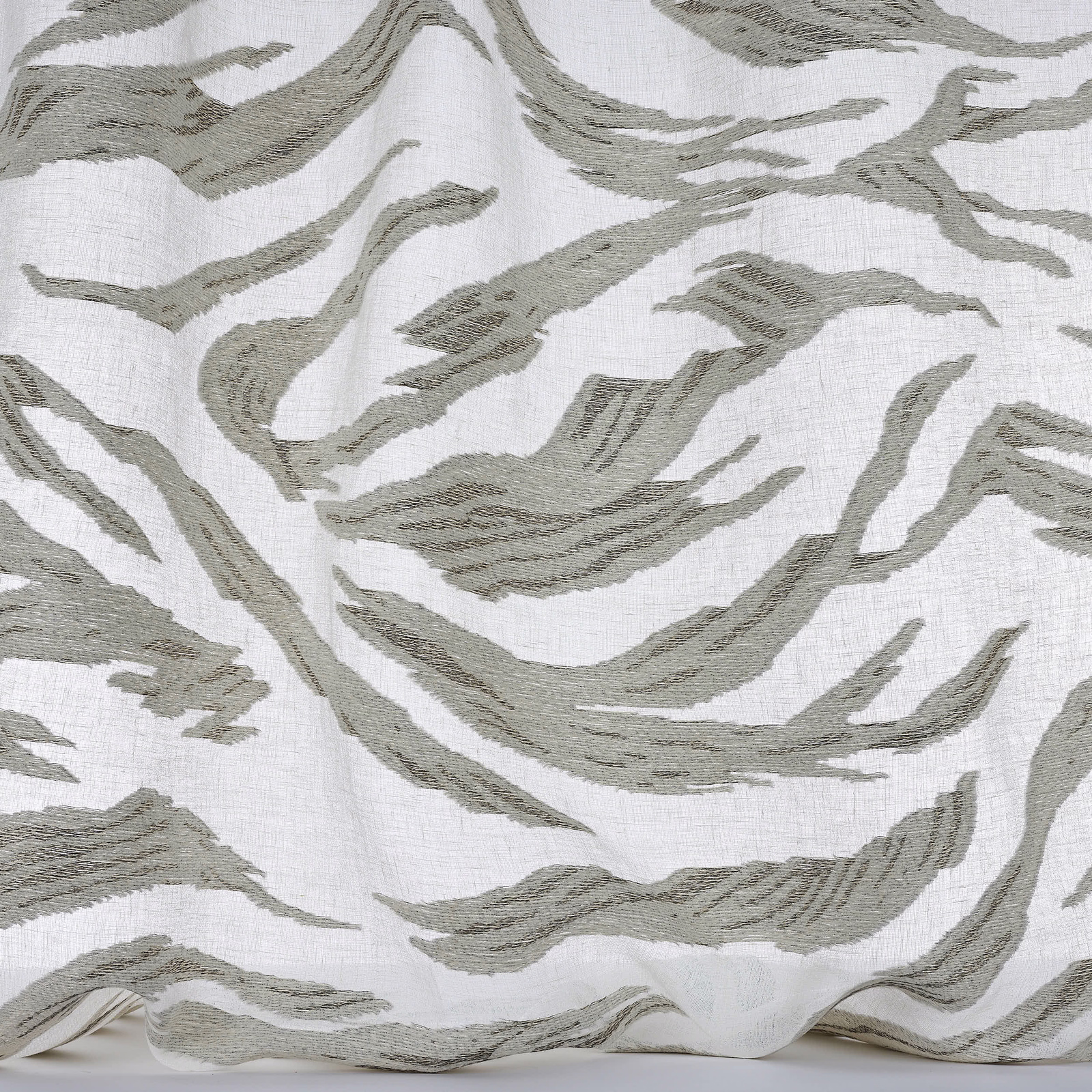 White fabric with large olive-grey abstract brushstroke pattern and textured weave