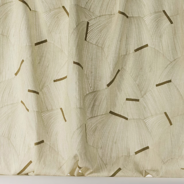 Cream-sand woven fabric with scattered tan geometric marks and soft drape