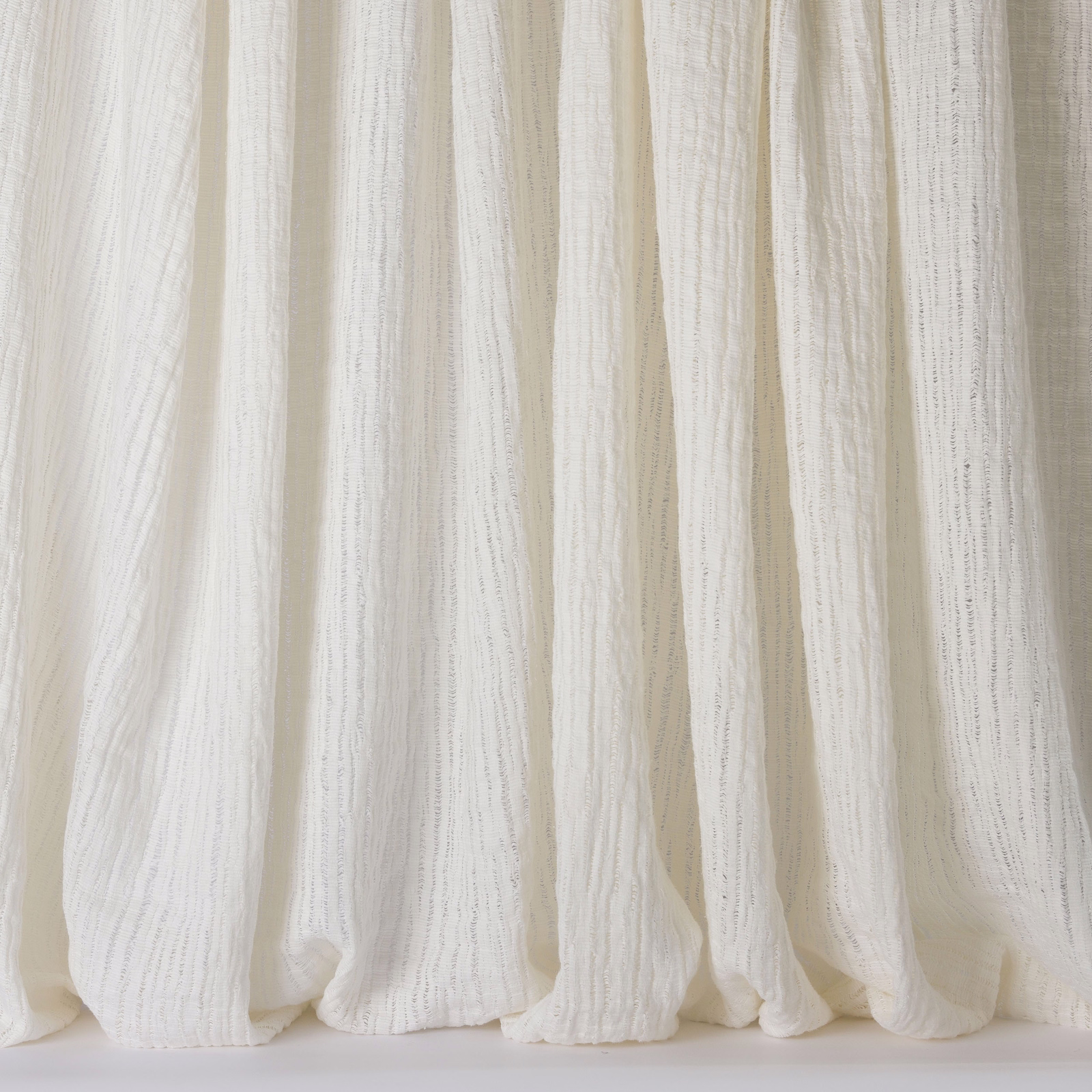 Soft ivory-white linen curtains with a fine slubbed texture and relaxed vertical folds