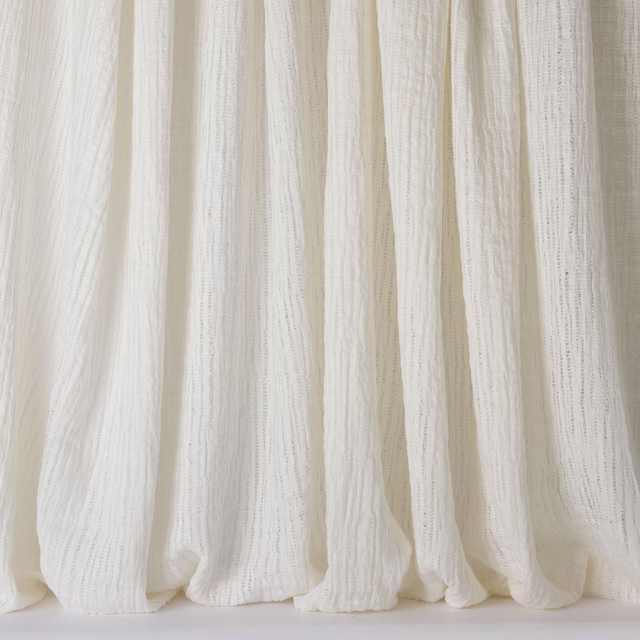 Soft ivory-white linen curtains with a fine slubbed texture and relaxed vertical folds
