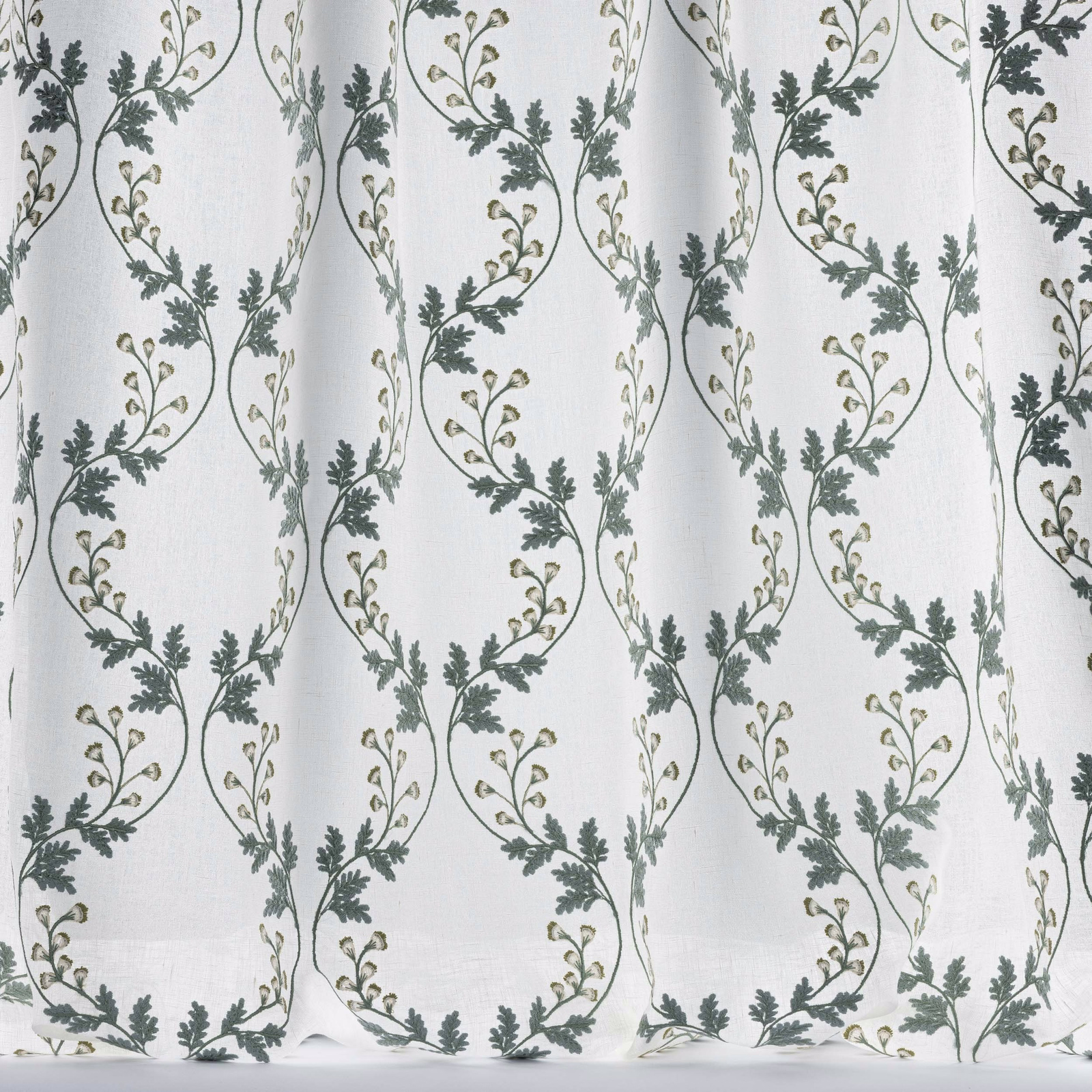 Sheer white fabric with trailing embroidered vine loops in muted old blue