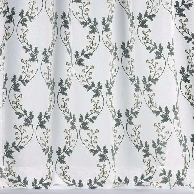 Sheer white fabric with trailing embroidered vine loops in muted old blue