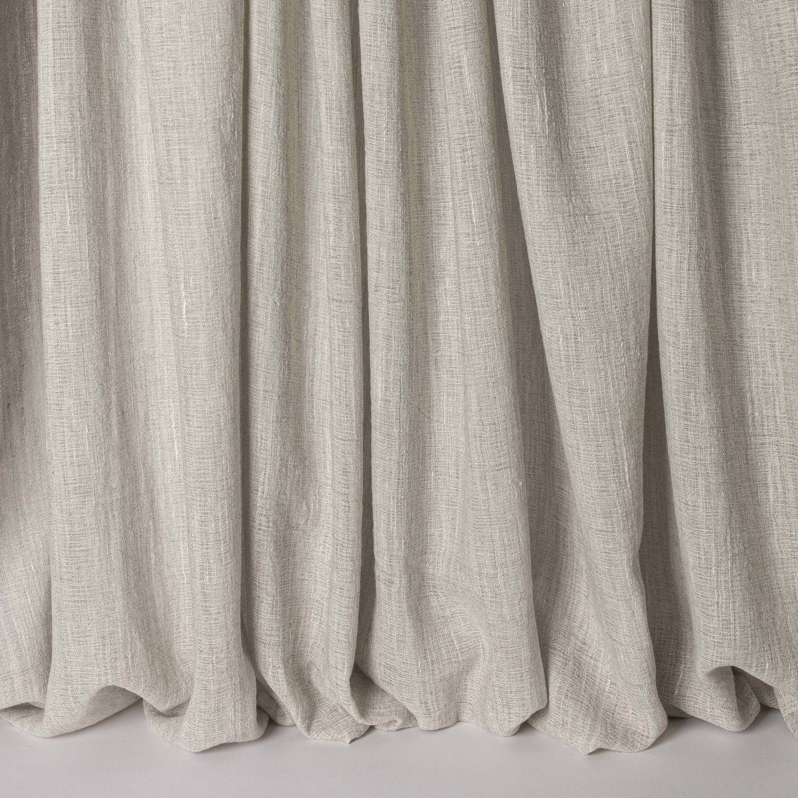 Soft warm grey linen-blend fabric hanging in gentle vertical folds