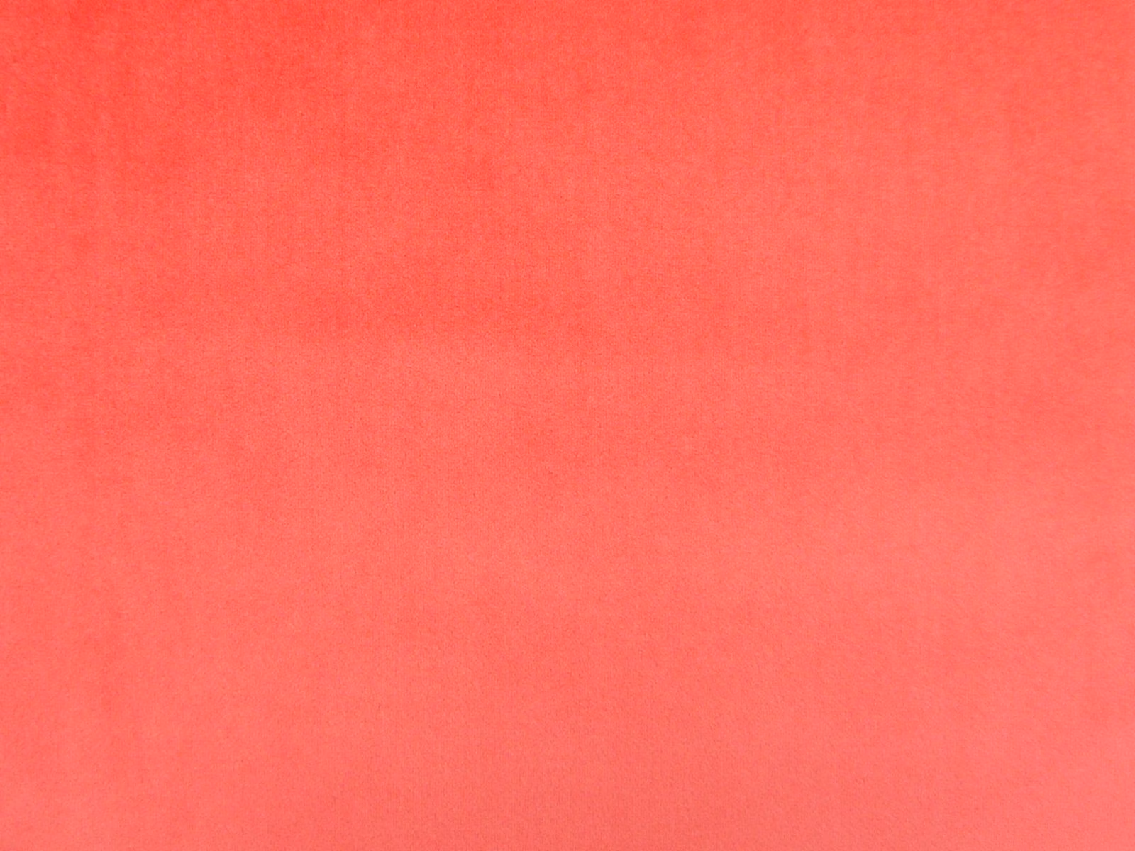Warm coral-red velvet swatch showing a fine, softly shifting pile