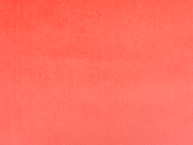 Warm coral-red velvet swatch showing a fine, softly shifting pile