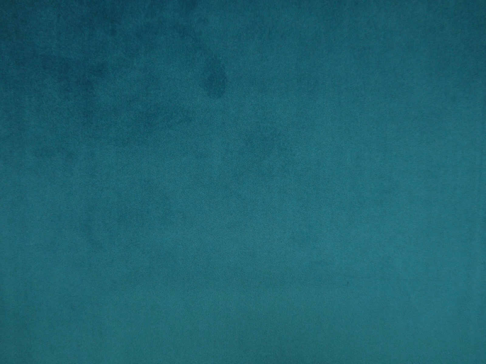 Close-up of mottled deep teal velvet with softly shifting blue-green pile