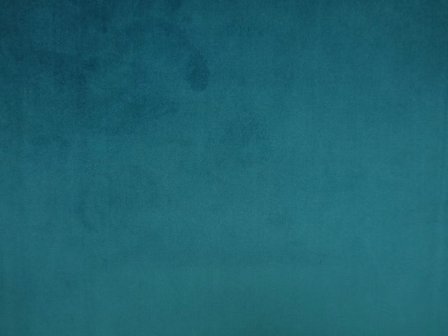 Close-up of mottled deep teal velvet with softly shifting blue-green pile