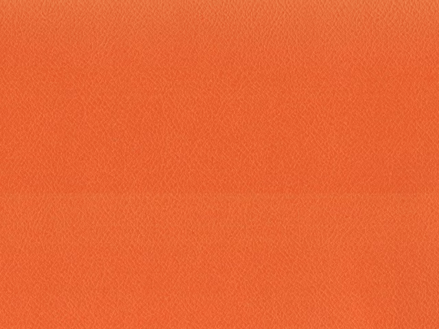 Warm coral-orange faux leather showing a subtle, even pebbled grain