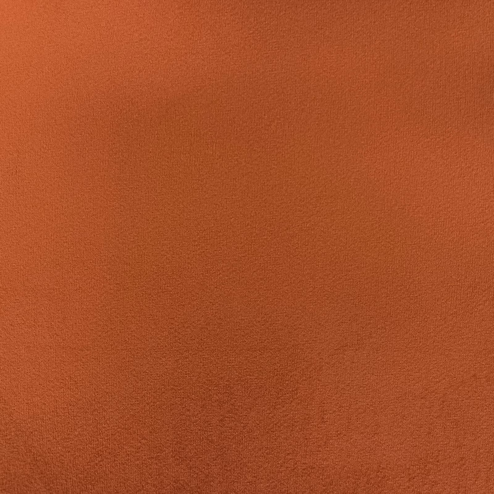 Close-up of burnt terracotta velvet with a softly brushed, shaded surface